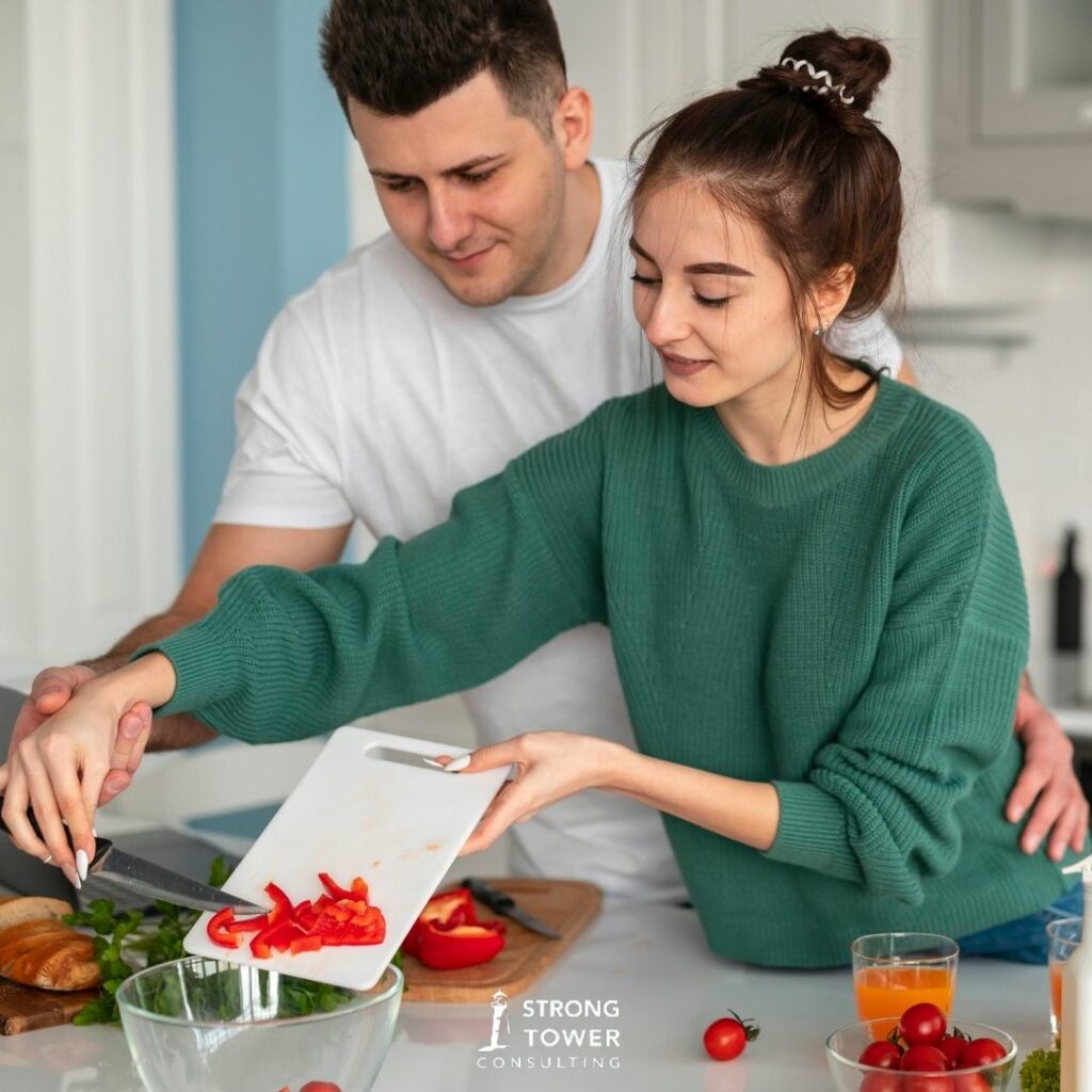 Couple cooking together by chopping tomatoes. 