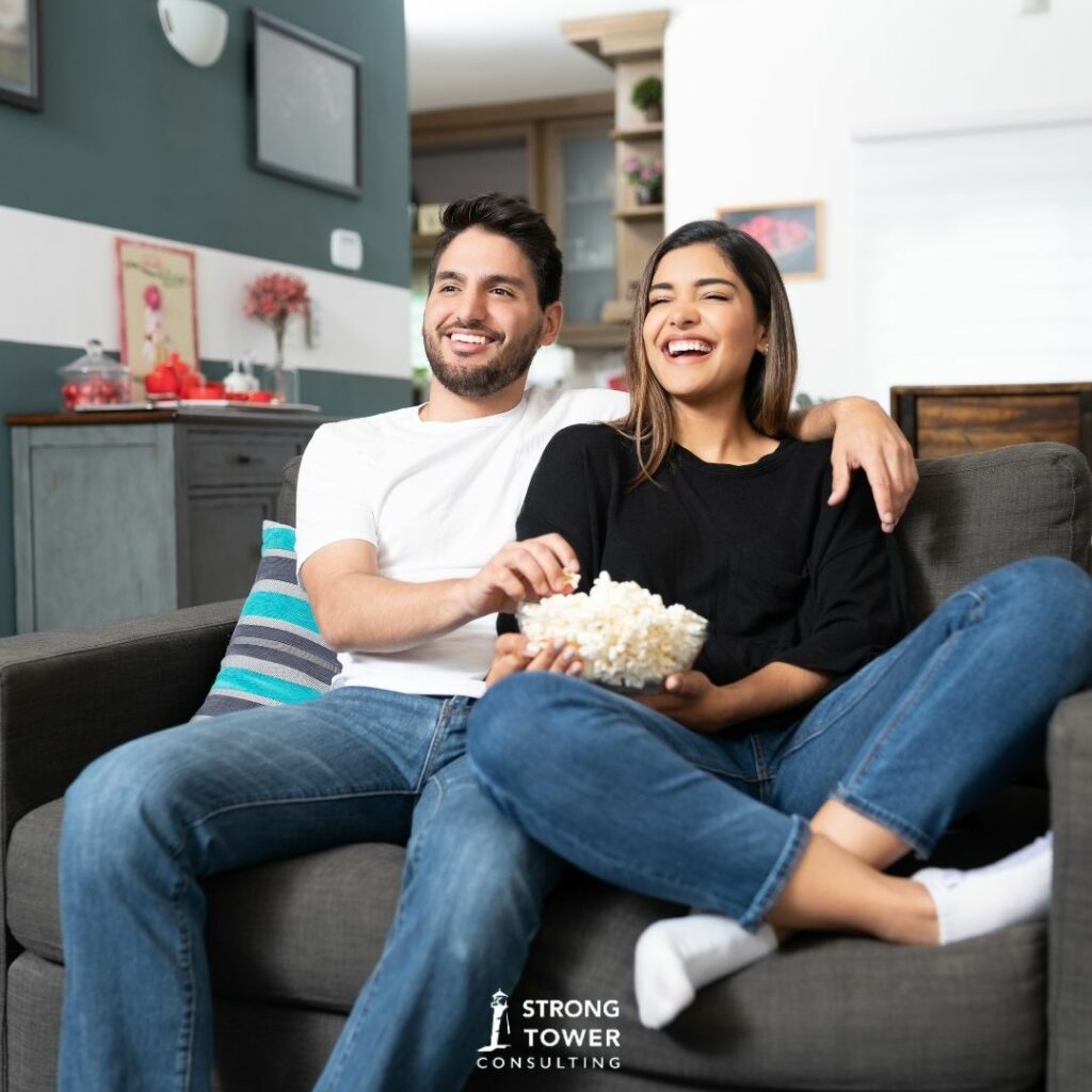 Couple watching a movie at home with popcorn.