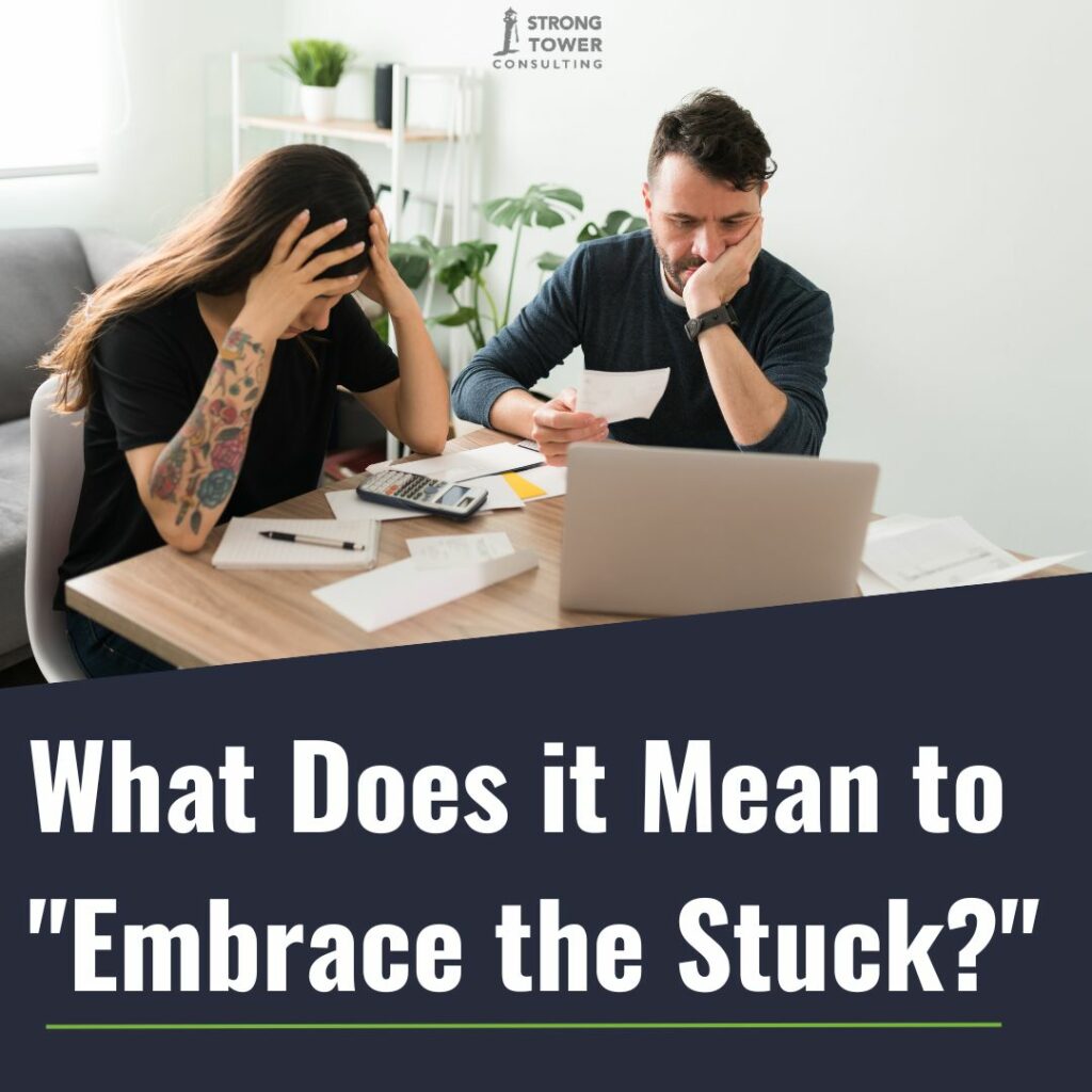 Couple sitting in front of a computer and calculator looking stressed.